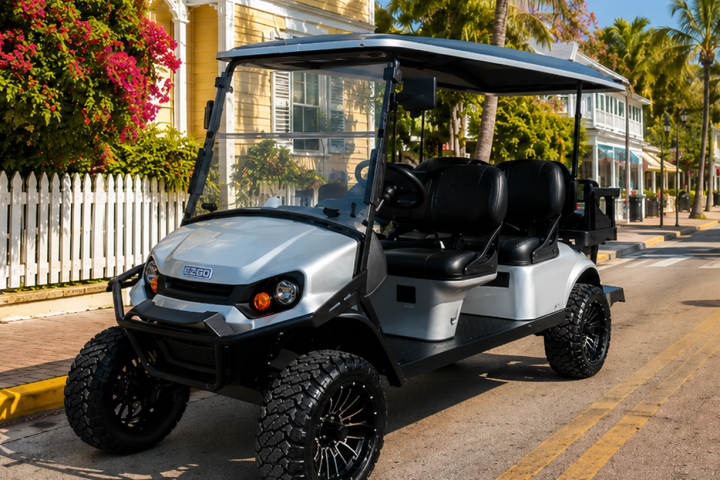 A white golf cart parked on a sunny palm-lined street.