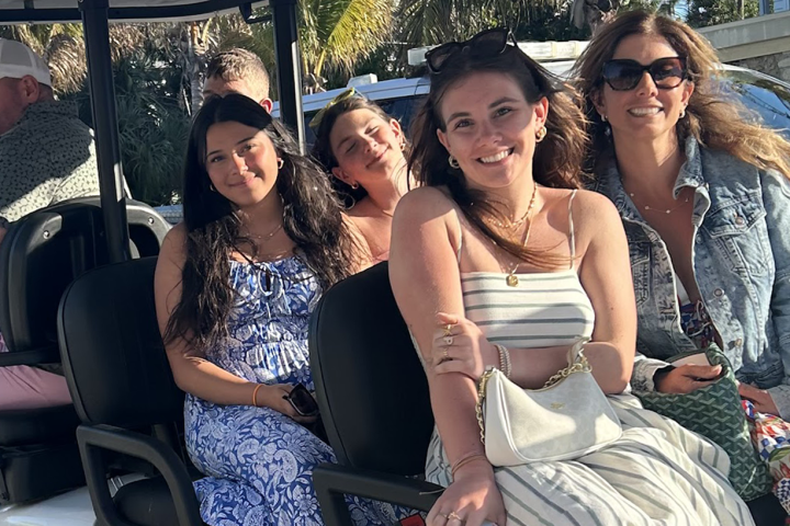 Group of people smiling in a golf cart on a sunny day.