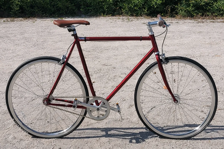 Red vintage-style bicycle on a gravel path.